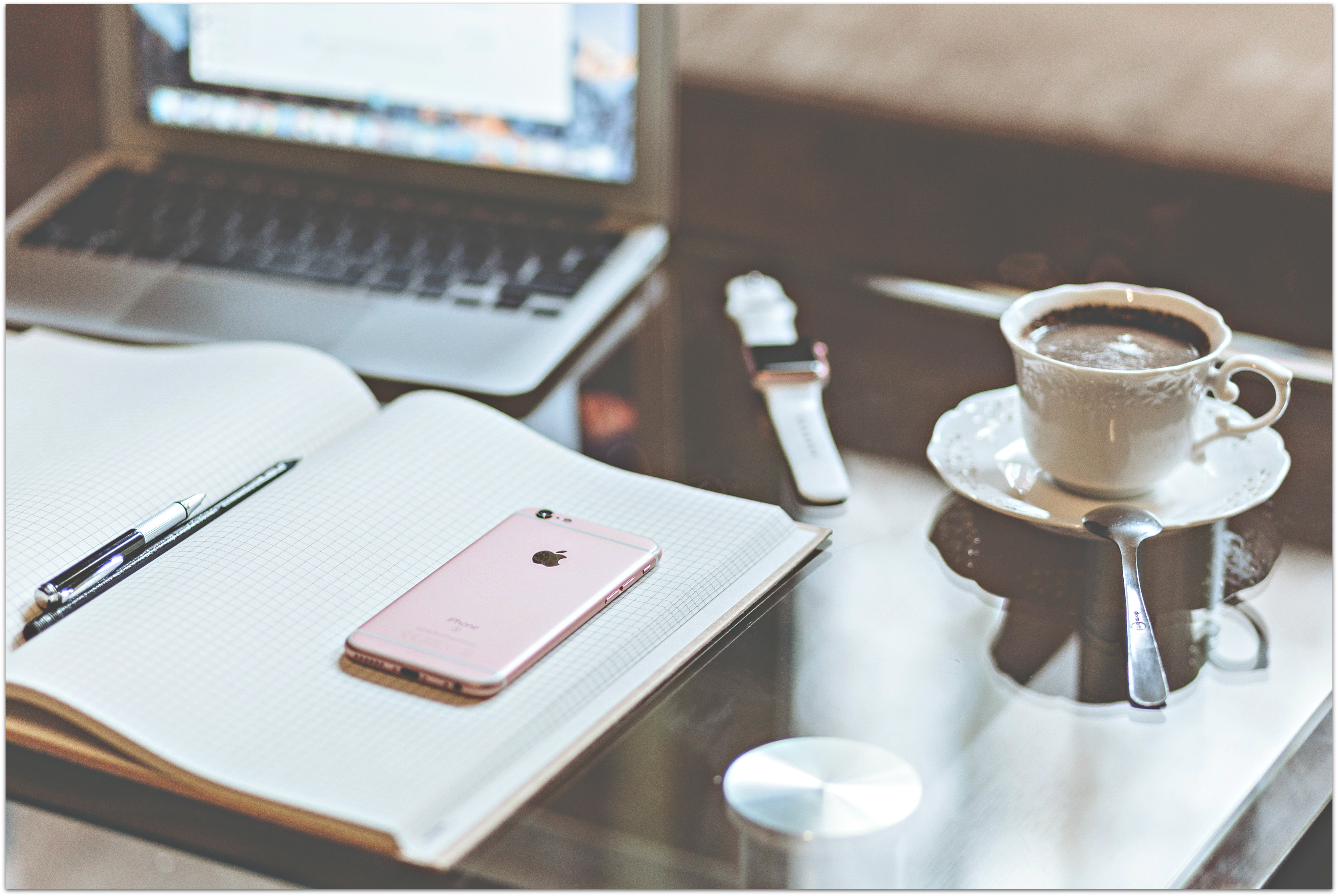 Desktop with laptop computer, open journal, pen, iPhone, cup of coffee