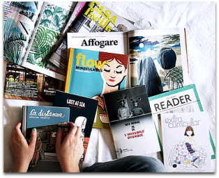 A pair of hands holding one magazine against a large pile.