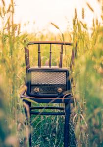 Antique radio on chair in a field to represent music.
