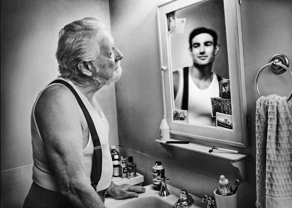 Old man looking in mirror at his younger self